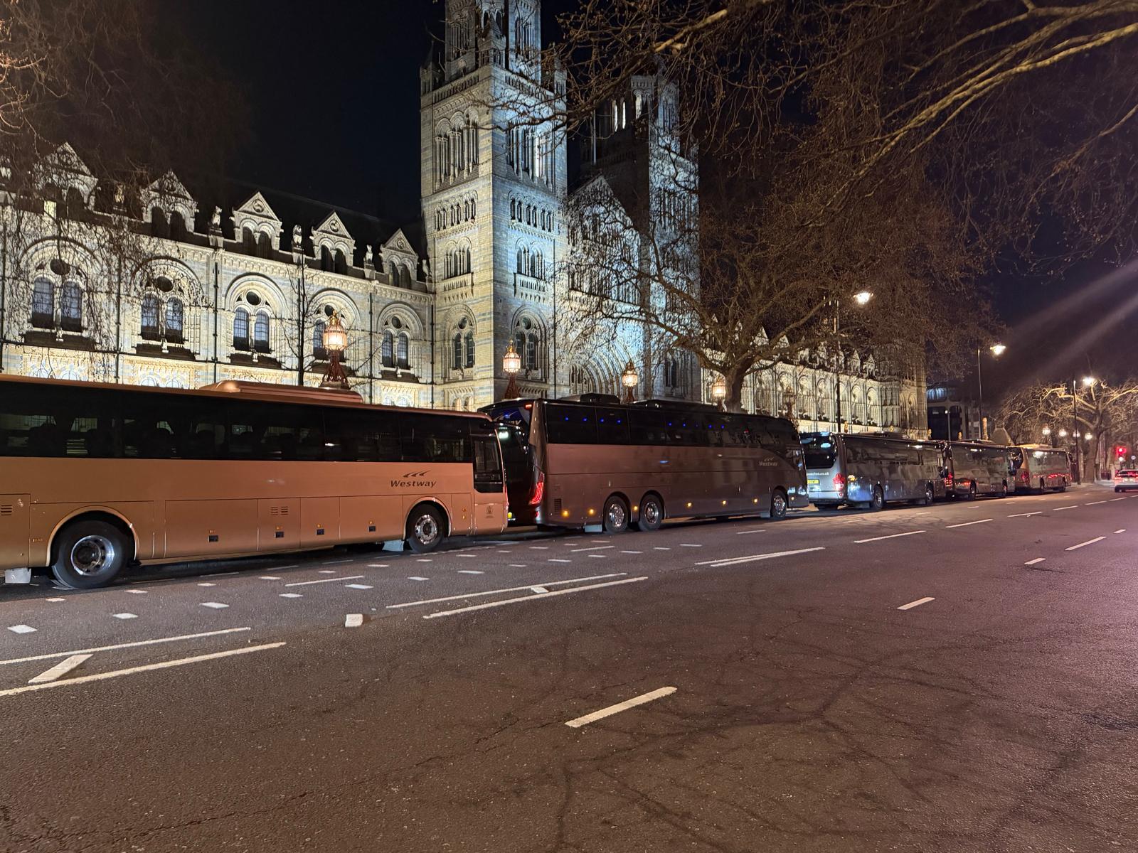 Westway coaches lined up outside an illuminated London venue at night